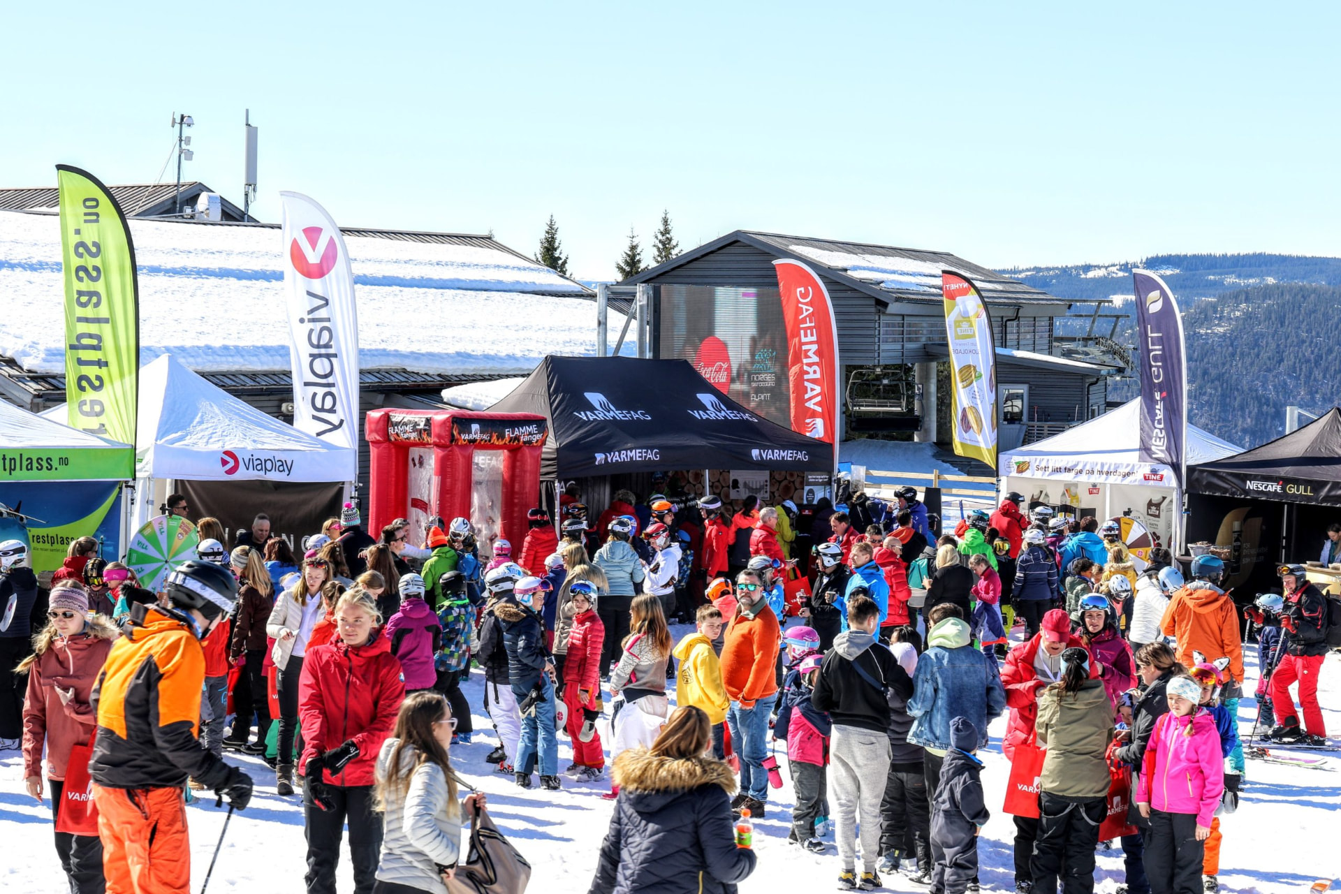 Stands og publikum i skibakken en solfylt dag