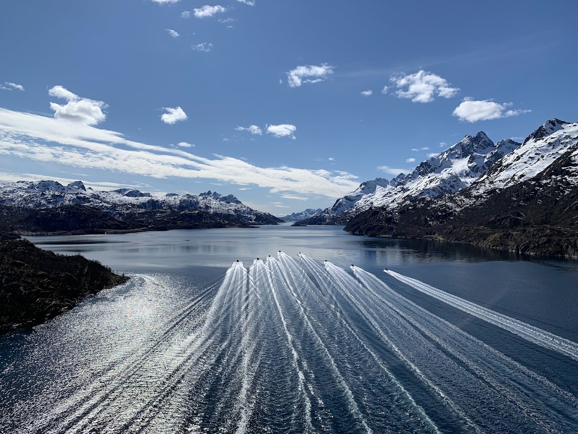 RIB-flåte i formasjon mellom snøkledde fjell i Lofoten